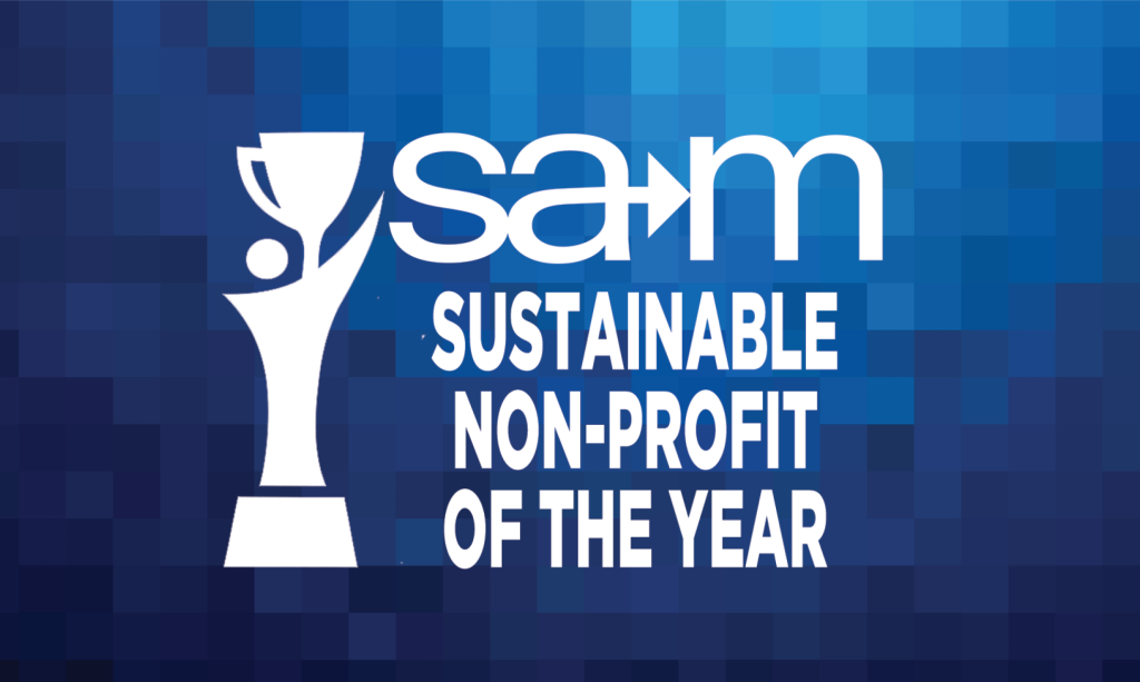On a blue pixelated gradient background, a white stylized figure holds up a trophy beside the white SAM logo with an integrated arrow, and below it the bold white text reads “Sustainable Non‑Profit of the Year.”